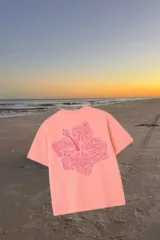 Remerón rosa con estampa de una flor de hibisco con detalles intrincados y la frase 'Glassy Waves' en la parte inferior.