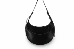 Cartera negra de cuero sintético con forma de media luna y costuras blancas.