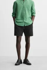 Bermuda negra regular fit confeccionada en tejido de algodón con estructura. Cintura elástica ajustable con cordón, bolsillos laterales y bolsillo trasero de vivo.
