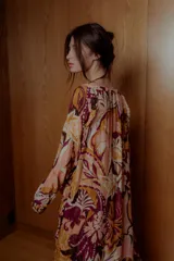 Maxi vestido con estampado floral en tonos naranja, rosa y borgoña. Tiene escote off-shoulder elastizado y mangas cortas con volados.