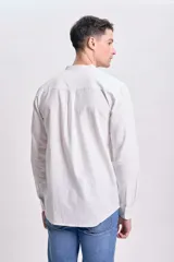 Camisa blanca de manga larga con cuello mao y cierre frontal con botones.