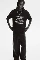 Remera negra de corte holgado con estampado frontal con la frase "Keep your friends close and your enemies far away".
