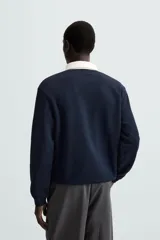 Sudadera azul marino de corte regular con cuello polo blanco de solapa y cierre frontal de botonadura oculta.