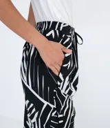 Pantalón pijama fluido de viscosa con estampa geométrica en blanco y negro. Tiene cintura media con ajuste de cordón con puntera metálica, bolsillos y prega frontal.