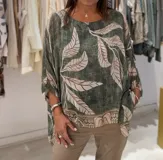 Blusa verde con estampado de hojas beige, cuello redondo y corte asimétrico.