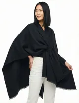 Ruana de tejido soft color beige, con cuello en V y un lazo o pasador frontal para ajustar. El ruedo tiene terminación desflecada.