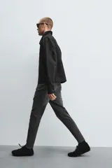 Pantalón de jean negro ajustado al cuerpo desde la cintura hasta el tobillo, de tiro medio y tejido elástico. Diseño de cinco bolsillos con lavado efecto roto y cierre frontal con cremallera y botón.