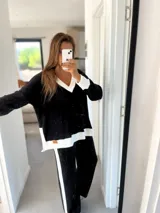 Conjunto de tejido de punto morley negro con detalles en blanco, compuesto por un sweater de escote en V y un pantalón de corte recto con una franja blanca lateral.