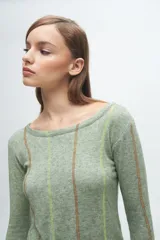 Remera gris de corte ajustado, con cuello redondo y mangas largas. Presenta líneas verticales bordadas en color verde claro y blanco.