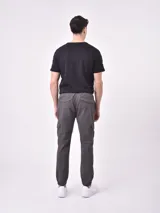 Pantalón jogger gris oscuro con cintura elástica ajustable con cordón, bolsillos laterales y bolsillo cargo con solapa en la pierna. Puños elásticos en los tobillos.