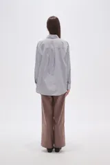 Camisa de algodón holgada con cuello camisa, botones frontales y estampado de rayas verticales finas en blanco, negro y rosado.