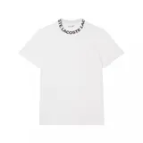 Remera blanca de corte clásico con cuello redondo y mangas cortas. El cuello presenta la inscripción "Lacoste" en negro.