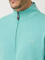 Buzo con cierre color verde agua, de algodón pima, con cuello alto, mangas largas y bolsillos internos.