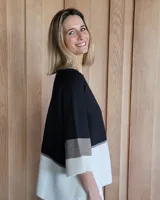 Buzo de punto con mangas 3/4, corte amplio y diseño a bloques de color negro, gris y blanco.