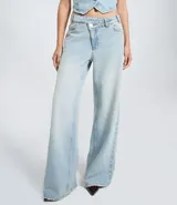 Pantalón de jeans azul de corte wide leg, tiro medio, con cintura de diseño traspasado y cierre tradicional.