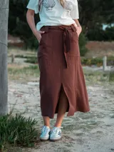 Falda midi marrón con lazo en la cintura, bolsillos laterales y tajo frontal.