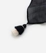 Pareo rectangular de gasa chiffon con estampado geométrico en blanco y negro, y borlas bicolores en las puntas.