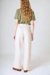Pantalón negro de corte ancho y tiro alto, con pinzas en la cintura y bolsillos laterales.