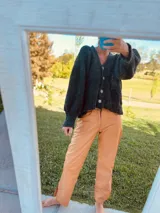 Cárdigan tejido de boucle color gris oscuro, con escote en V, mangas largas abullonadas y cierre frontal con botones grandes. Corte holgado.