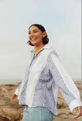 Camisa celeste y blanca a rayas verticales, de corte holgado y mangas largas con puños abotonados.