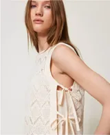 Top sin mangas de encaje color crema, con cuello redondo y detalle de lazos en los laterales.