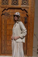 Camisa blanca de lino con bordados dorados de árboles, corte recto, cuello camisero y mangas largas con puños abotonados.