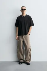 Pantalón de jean color marrón topo, de corte holgado y amplio en toda la pierna, con tiro medio, cinco bolsillos, efecto lavado, detalle de pinzas en perneras y cierre frontal con cremallera y botón.