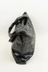Bolso negro de cuero sintético con tachas plateadas y argollas metálicas.