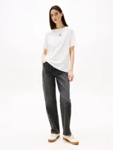 Remera blanca de corte relaxed con cuello redondo y logo Tommy Hilfiger gráfico estampado en el pecho.