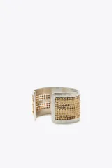 Pulsera rígida plateada con apliques de malla metálica dorada.