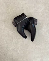 Botín de cuero vacuno color bronce con puntera y caña en cuero negro. Diseño con borde superior en zigzag y taco de madera.