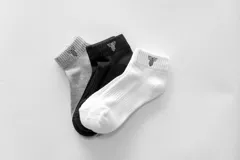 Pack de tres pares de medias soquete unisex, una gris, una negra y una blanca, con logo en el tobillo.