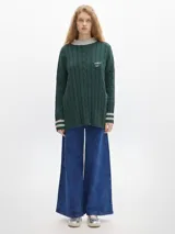 Buzo verde oscuro de tejido de punto con cuello alto y mangas largas. Tiene un pequeño logo bordado en el pecho y puños y cuello en color beige con rayas horizontales.