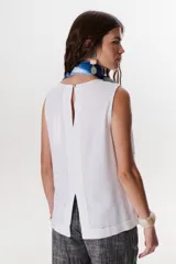 Top sin mangas color terracota con cuello redondo y bolsillo frontal. Presenta costuras a contratono en blanco que definen los bordes y el bolsillo.