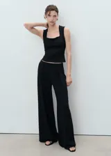 Top sin mangas color negro, de tejido elástico y diseño entallado, con escote cuadrado y tirantes anchos.