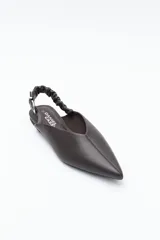 Zapato destalonado de punta fina, color negro, con base baja y tira trasera elástica con hebilla metálica ajustable. Diseño minimalista.