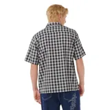 Camisa de manga corta con cuello camisero y botones frontales. Presenta un estampado de cuadros (plaid) en blanco y negro. Posee un bolsillo de parche en el pecho izquierdo con un pequeño logo bordado en blanco.