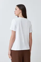 Remera blanca de algodón con cuello redondo y bordado de flores en el frente.