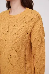 Sweater de punto color mostaza, con diseño de trenzas y puños acampanados.