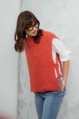 Chaleco de punto grueso color coral, con cuello alto y sisas amplias.