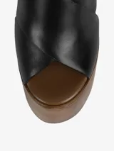 Sandalia negra con plataforma de madera y tira trasera ajustable con hebilla.