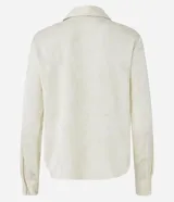 Camisa color crema en crepé con cuello solapa, abotonado frontal, mangas largas y textura de flores tramadas en el tejido.