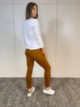 Pantalón terracota de algodón con corte ajustado, cintura plisada, bolsillos funcionales y cinturón con estampado animal print.