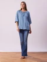 Blusa celeste de tencel, marca Marissa Olivia, con cuello a la base, escote en V con aplique de cordel y lazo de ajuste. Manga larga amplia con puño elastizado.