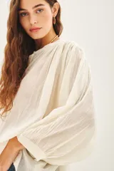 Camisa amarilla de algodón con corte amplio, cuello redondo y mangas 3/4 con puños elásticos.