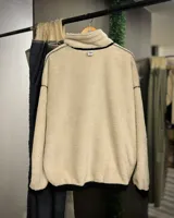 Buzo beige de pana con cuello alto forrado en corderito blanco, cierre parcial con cremallera, puños y cintura elastizados.