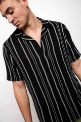 Camisa negra con rayas verticales plateadas, de manga corta y cuello americano.