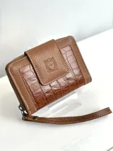 Billetera pequeña de cuero color marrón, con textura tipo cocodrilo en los laterales y cierre con cremallera. Incluye correa de muñeca.