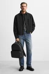 Mochila negra con acabado grabado, compartimento principal con cierre de cremallera, bolsillo interior con cremallera, bolsillo frontal con cremallera, asa de mano, dos asas de hombro ajustables, parte posterior acolchada y banda de sujeción para equipaje.
