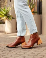 Botas de cuero color marrón, hechas a mano, con punta en pico y taco de madera cuadrado. Cierre lateral con cremallera.